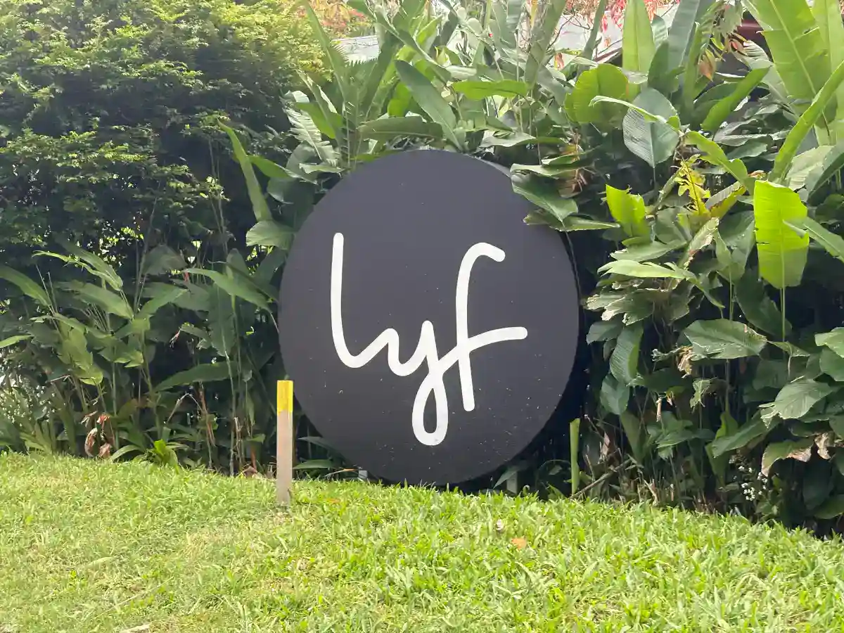 Lyf One-North Singapore signage. Round black sign with "lyf" in white script, surrounded by greenery.